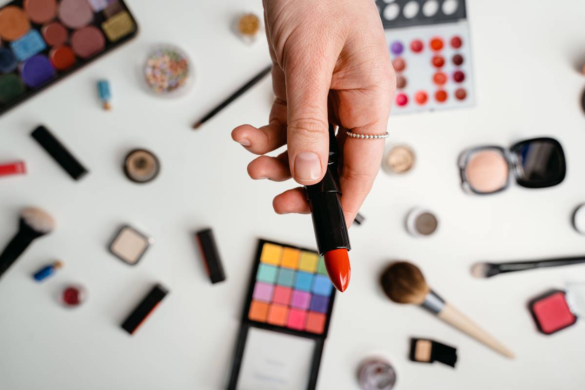 A hand holding affordable drugstore makeup products beside a written note saying low price beauty hack